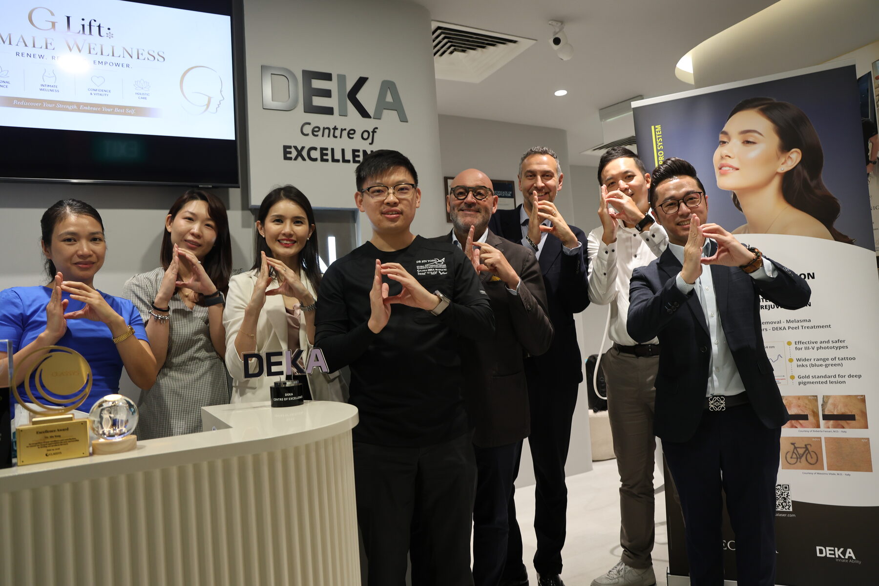 Dr Sin Yong, the clinic team and the DEKA delegation beneath the Centre of Excellence signage