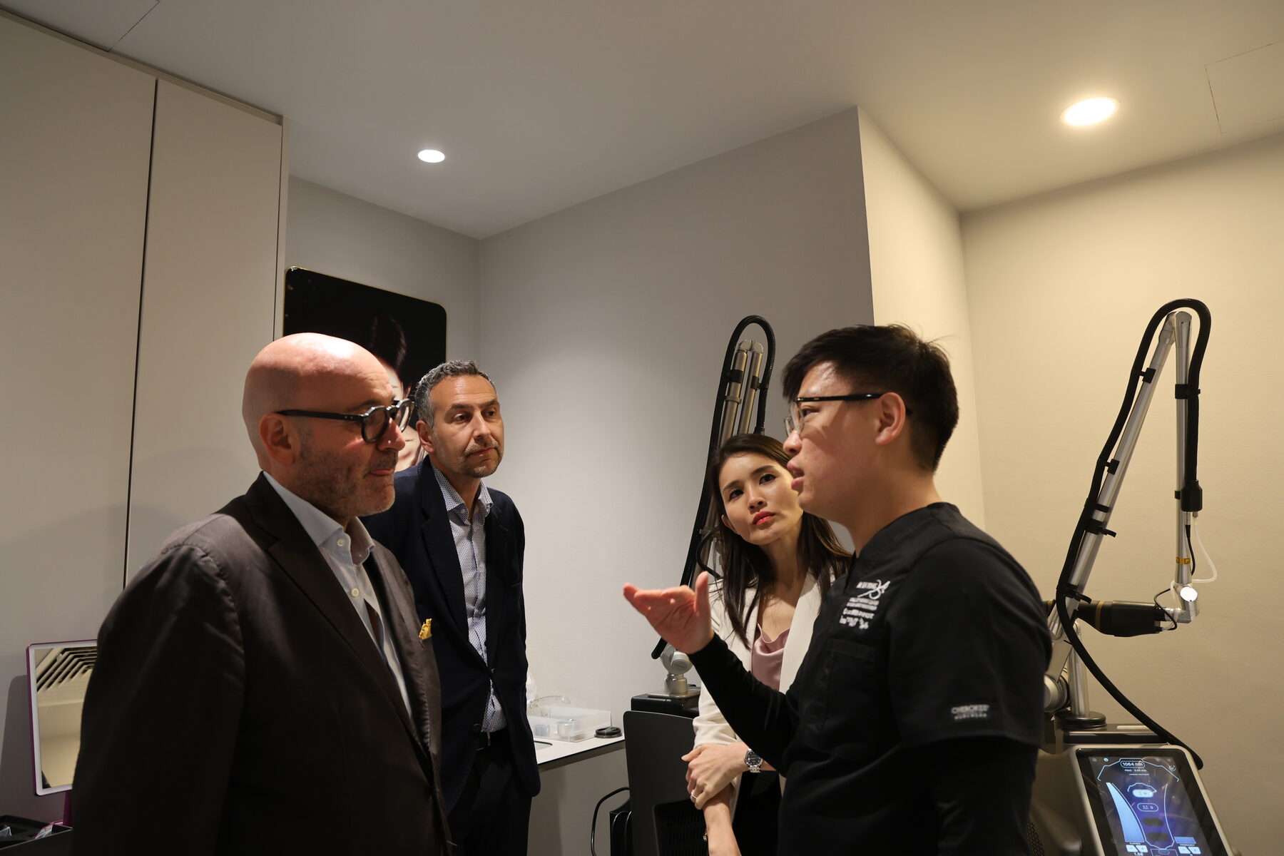 Dr Sin Yong discussing protocol design with the DEKA delegation beside a laser platform in the treatment room