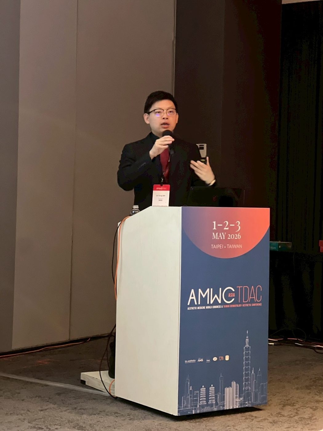 Dr Sin Yong presenting at the AMWC Asia-TDAC 2026 lectern in Taipei, Taiwan